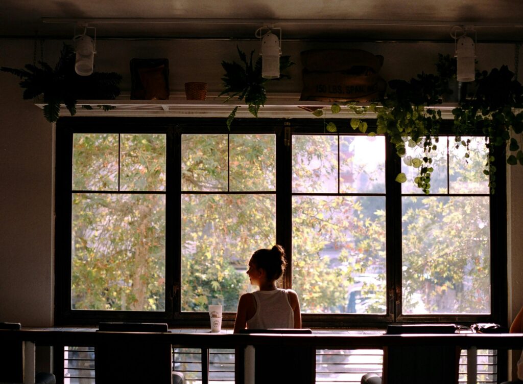 backview-of-woman-sitting-beside-the-window-on-a-cafe